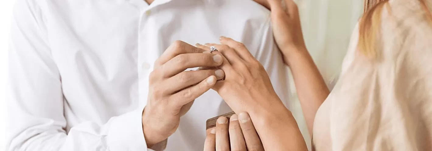 Un homme passe une bague au doigt de sa fiancée